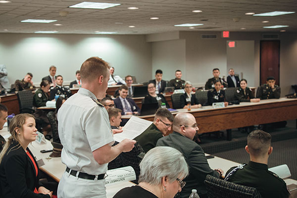 A student standing in a crowded room, presenting his policy paper during the MSC SCONA main conference.